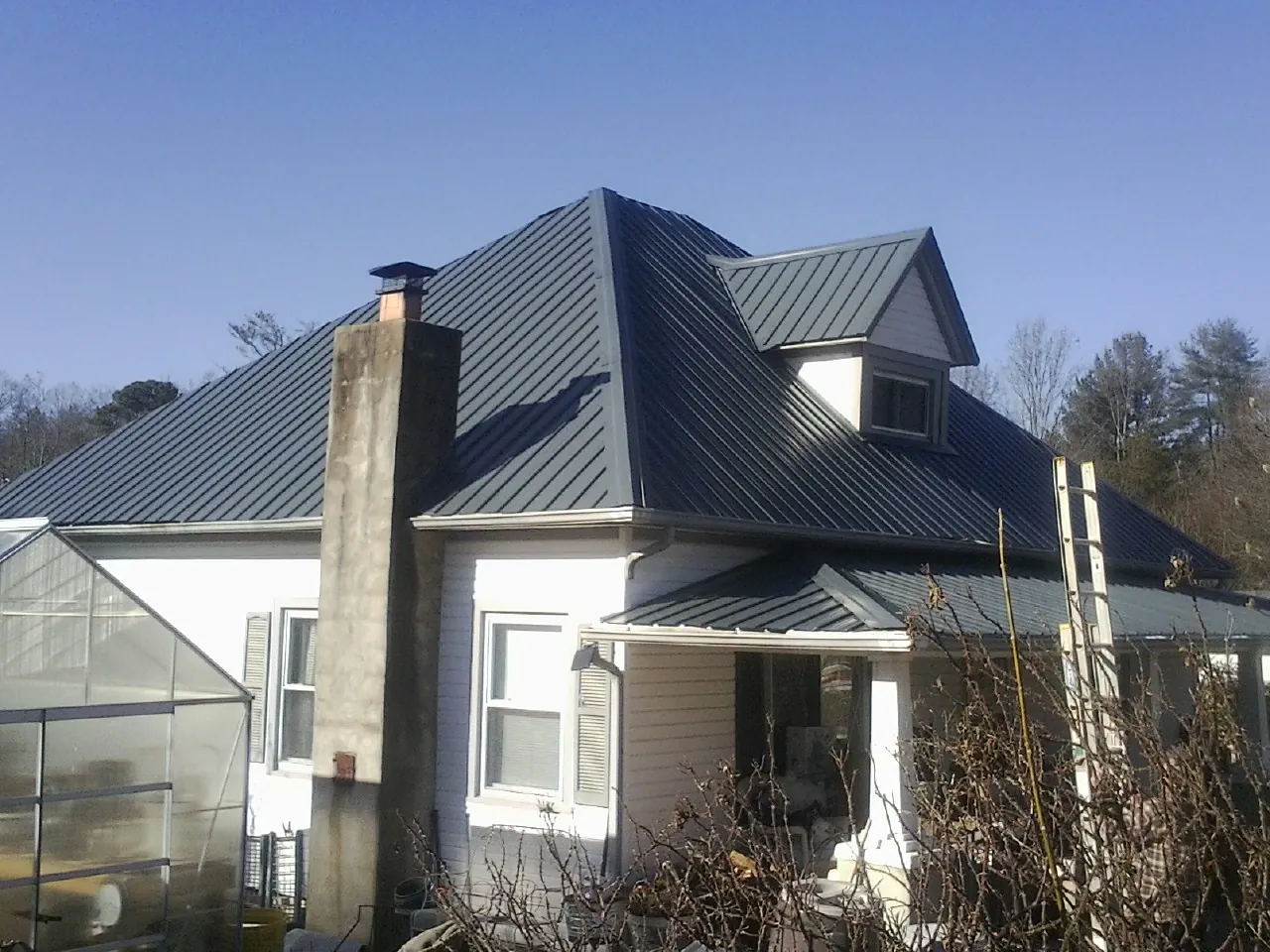 Dark blue standing seam metal roof on a white farmhouse with dormer — Slate & Tile Roof Repair by Roofing Brothers in Middle Grove