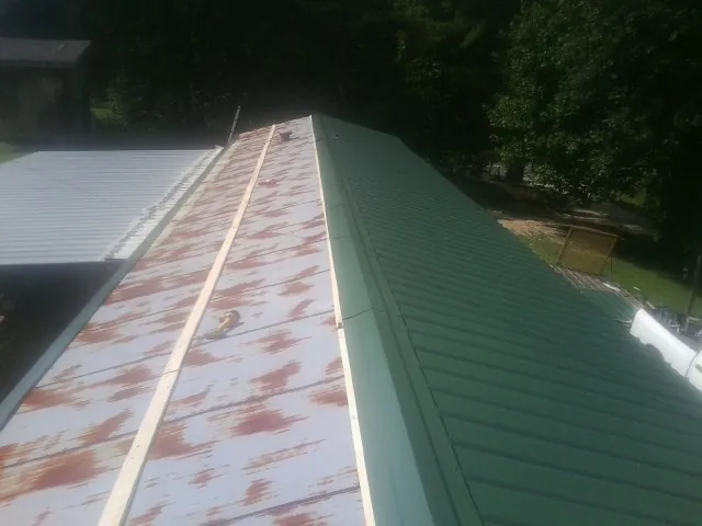 Old rusted panels beside newly installed green metal roofing — Wind Damage Roof Repair by Roofing Brothers in Middle Grove