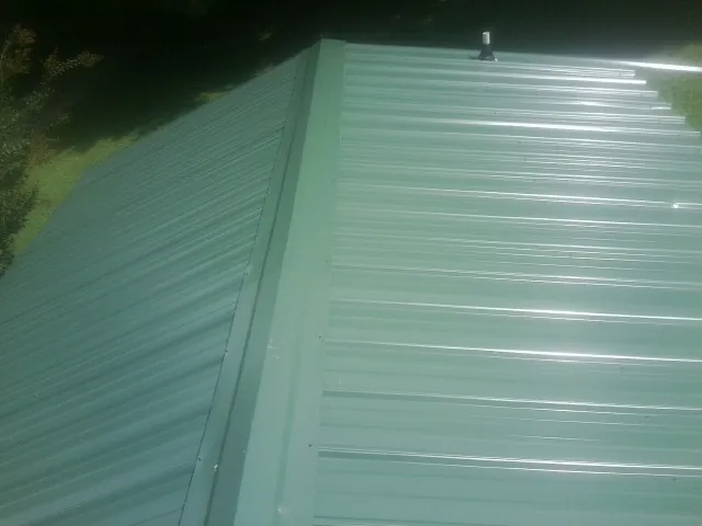 New green metal panels meeting at the ridge of a roof — Flat Roof Repair work by our crew in Middle Grove