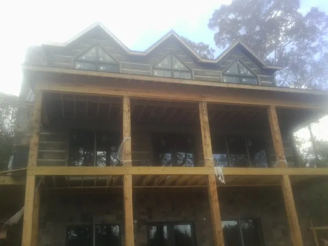 Dormers and porch framing on a large log home under construction — Roof Coating work by our crew in Middle Grove