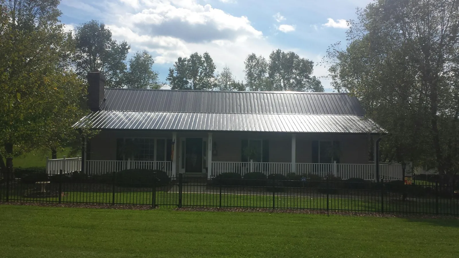 Gray metal roof on a brick ranch with a full width front porch — Gutter Guard Installation work by our crew in Middle Grove