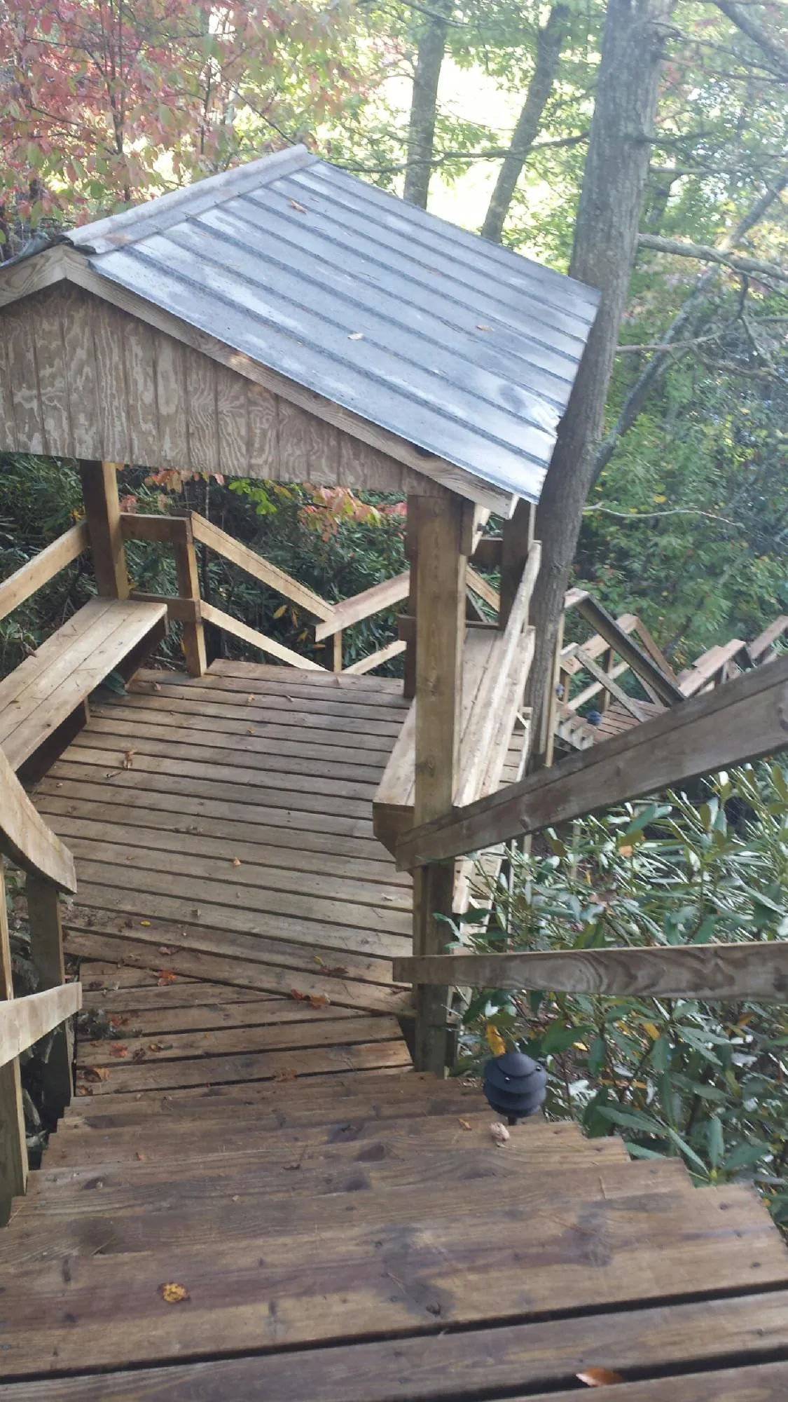Metal roofed shelter over wooden steps on a wooded walkway — Skylight Repair & Installation work by our crew in Middle Grove