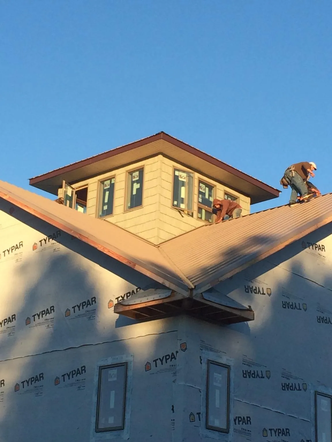 Roofers working around a rooftop cupola on a new metal roof at sunset — Roof Waterproofing in Middle Grove by Roofing Brothers